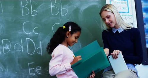 Teacher Helping Student in Classroom with Alphabet