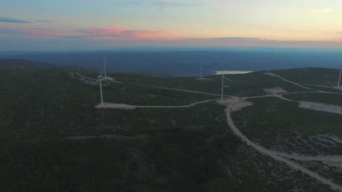 Aerial view of seven windmills for the production of electric energy, at sunset
