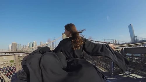 Frau im schwarzen langen fließenden Kleid geht über die Brooklyn Bridge in New York