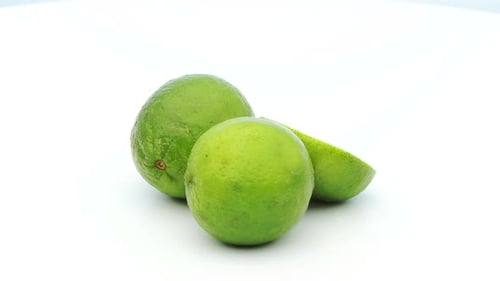Fresh Green Limes Rotating on White Surface
