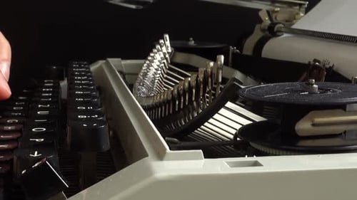 The man is typing on a retro typewriter.