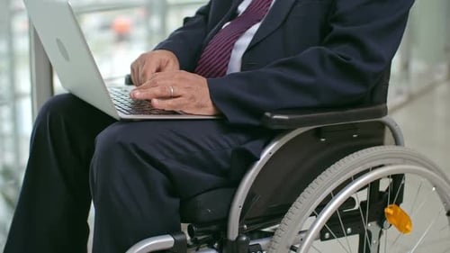 Adult in Wheelchair Uses Laptop in Office