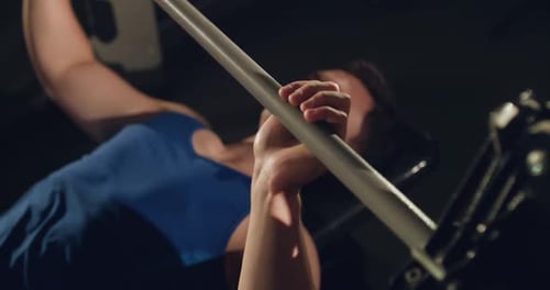 Top View of Young Muscular Athlete Lying and Doing Barbell Exercise in a Gym