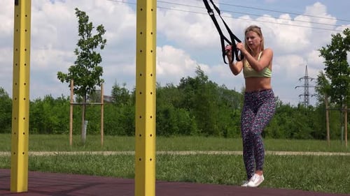 A Beautiful Fit Woman Does Assisted One-legged Squats at an Outdoor Gym
