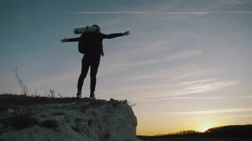 Silhouette of Traveler on Cliff at Sunset