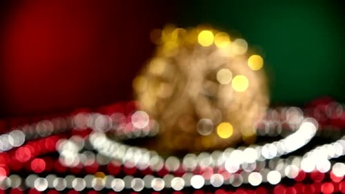 Ungewöhnliches Goldspielzeug für Weihnachten oder Neujahr und Perlen, Rotation, auf Rot und Grün, Bokeh, Dynamisch