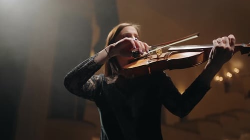 Woman Playing Violin in Concert Hall at Night