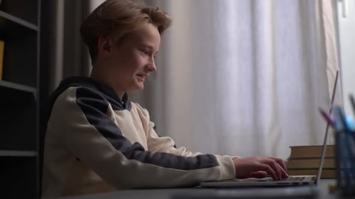 Side Closeup View of Cheerful Child Boy Using Typing Laptop Chatting with Friends Via Internet