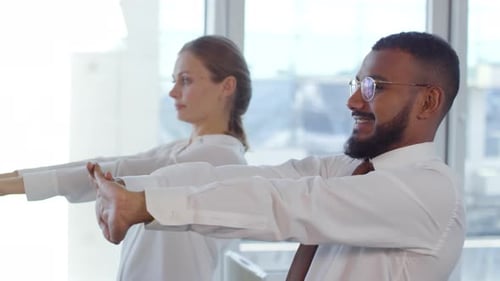 Office Workers Stretching Arms at Workplace