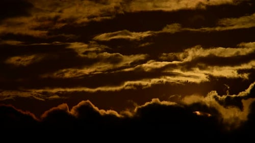 Golden Sunset Descends Behind Dark Wispy Clouds