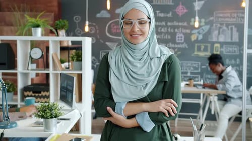 Retrato de una empresaria musulmana sonriente con un pañuelo en la cabeza de pie en la oficina creativa