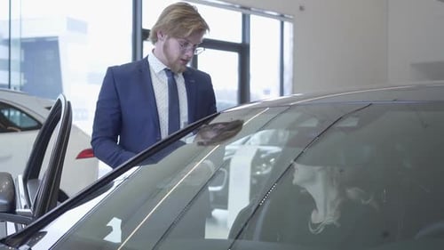 Handsome Young Car Salesman Discussing New Automobile Model in Motor Show. Car Dealership