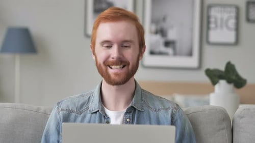 Man Video Chatting and Waving from Couch