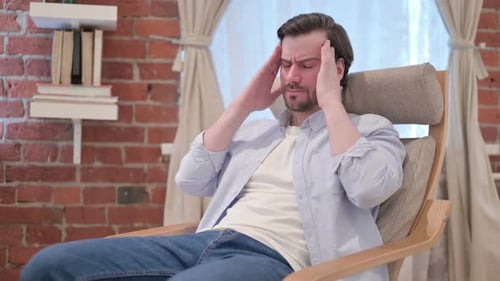 Young Man Having Headache While Sitting on Sofa