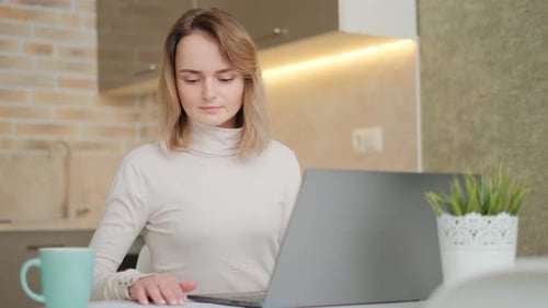 Young Woman Works on Laptop in Kitchen