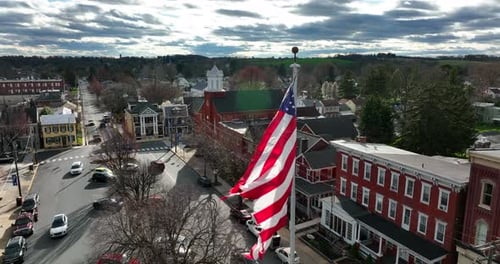 American Flag Waving Over Small Town Aerial Shot