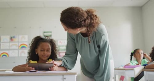Teacher Helping Student with Tablet in Classroom