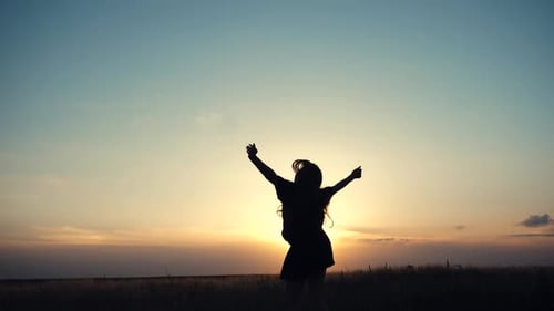Silhouette of Woman in Field at Sunset