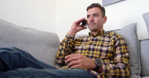 Adult Talks on Phone while Relaxing on Couch