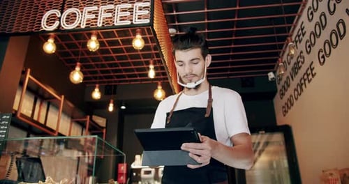 Alegre propietario de café masculino joven navegando por recetas de café con tableta digital