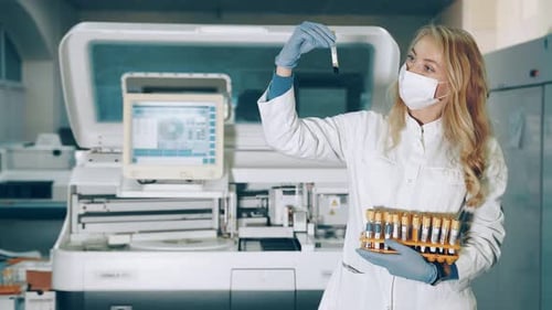 Female Scientist Examines Test Tubes in Lab