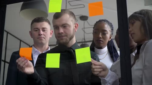 Team Brainstorming on Glass Wall in Modern Office