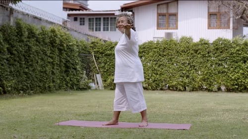 Asian Elderly woman pilates exercise in garden.