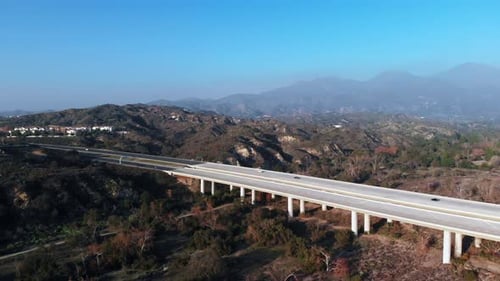 Aerial pull back from a bridge at an angle with mountain background.