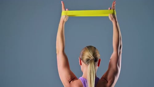 Woman Exercises Shoulders with Resistance Band Indoors