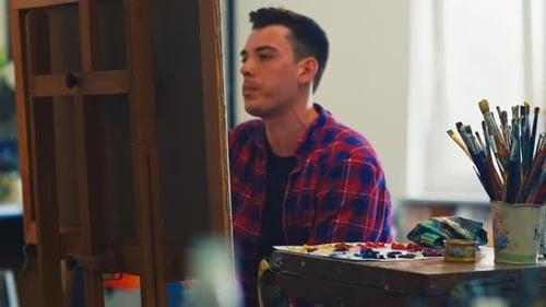 Young Adult Man Painting on Canvas in Art Studio