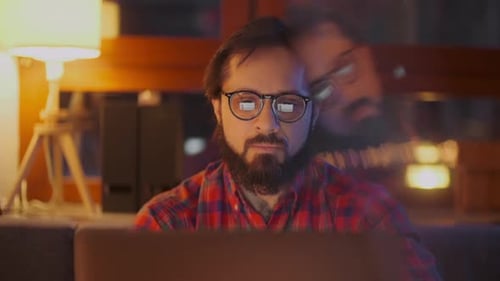 Porträt eines Mannes arbeitet nachts am Laptop mit Brille. Nahaufnahme. Geschäftsmann auf der Suche