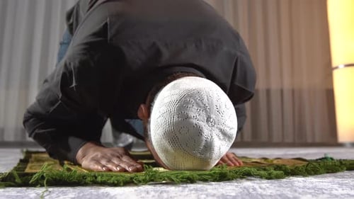 Man Kneels on Rug for Prayer