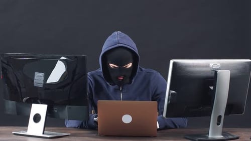 Masked Hacker Working at Computers, Frustrated
