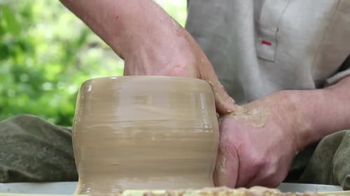 Un potier d'origine caucasienne fabrique un pot en argile brune, humidifie l'argile et dessine un moule