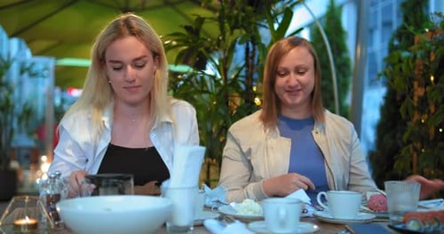 Daughter and Mother Take Off Blue Face Masks Sitting at Restaurant Table