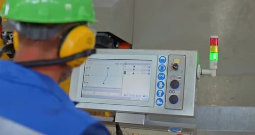 Factory Worker Sets Up a Computer to Control the Machine