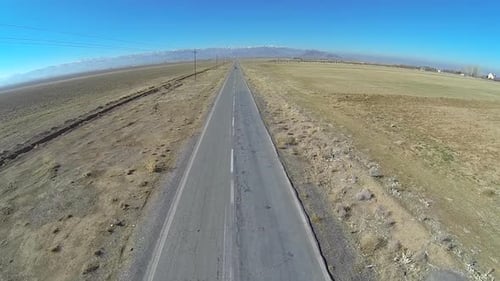 Aerial view of a car driving on an empty desert road.