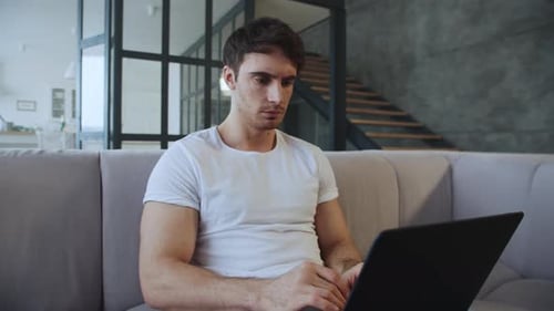 Man Working on Laptop While Sitting on Couch