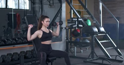 Young Female Training Gym Girl Lifts Dumbbell Weights While Sitting Bench Muscle Training Weights