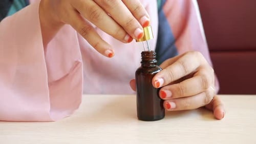 Women Hand Drop Falls From a Pipette Into a Cosmetic Bottle