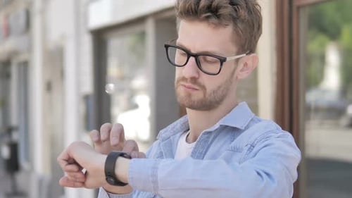 Young Man Using Smartwatch Outdoors in City