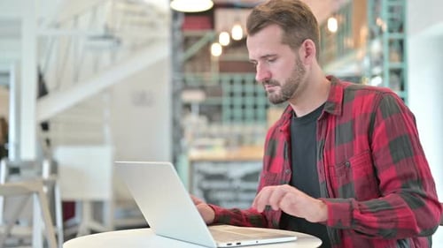 Junger Mann mit Laptop steht und geht weg