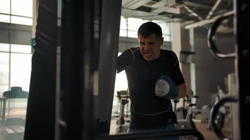 Aggressive Athlete Boxer Hits a Punching Bag in the Gym