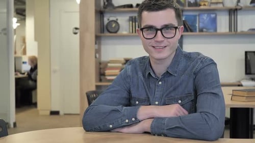 Thumbs Up By Creative Young Man in Glasses at Work