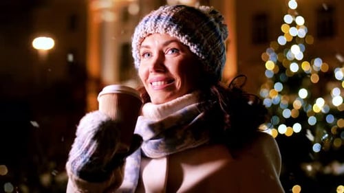 Smiling Woman Drinking Coffee in Snowy Christmas Scene