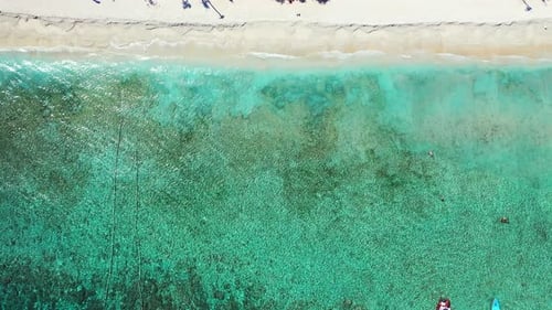 Wide fly over tourism shot of a sandy white paradise beach and aqua turquoise water background