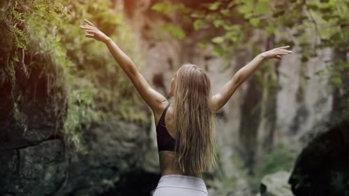 A Happy Young Woman is Raising Up Her Hands Standing Outdoors and Enjoying View of Nature
