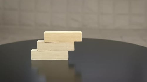 Hands Stacking Wooden Blocks on Black Table