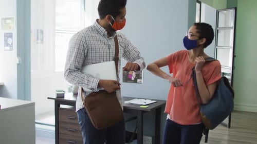 Masked Employees Elbow Bump in Modern Workplace