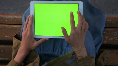 Woman Uses Tablet with Green Screen on Bench